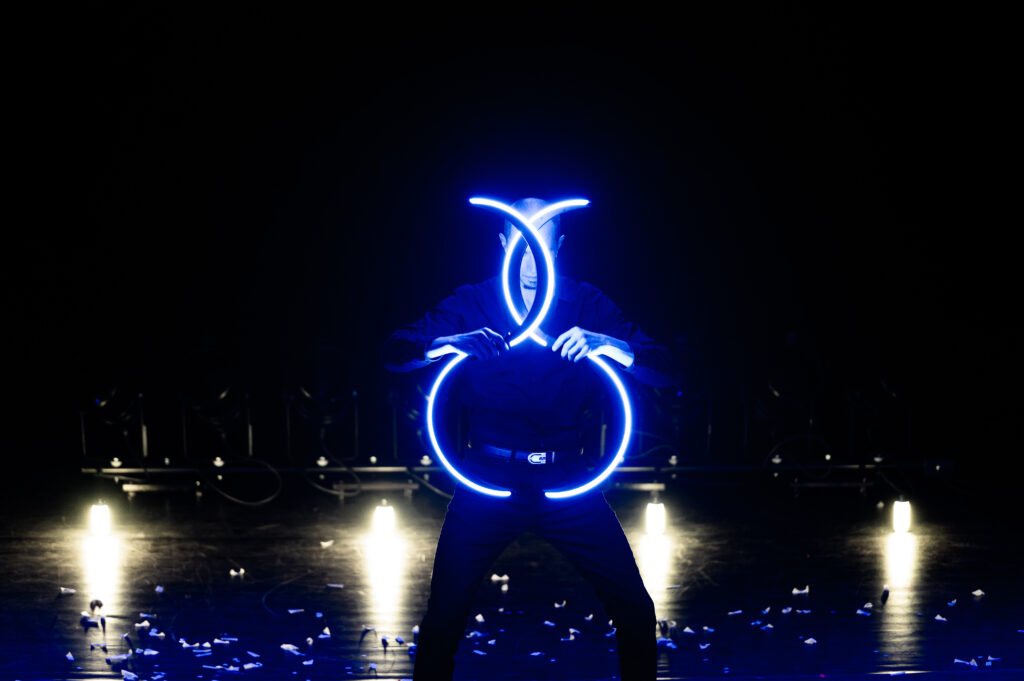 Un artiste sur scène qui manipule des buugeng LED (lumineux) de couleur bleue
