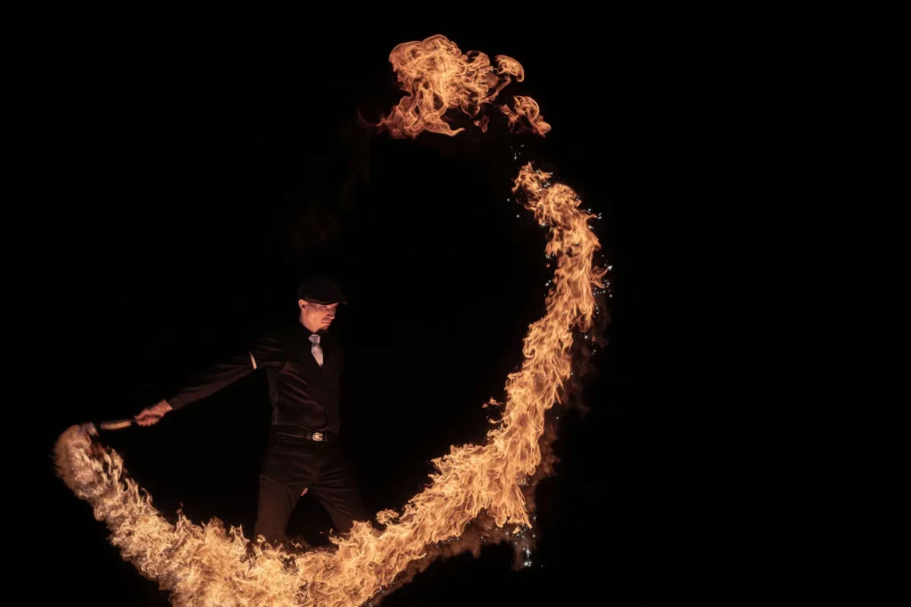 Show de rue nocturne avec pyrotechnie et jonglerie LED devant un public familial.