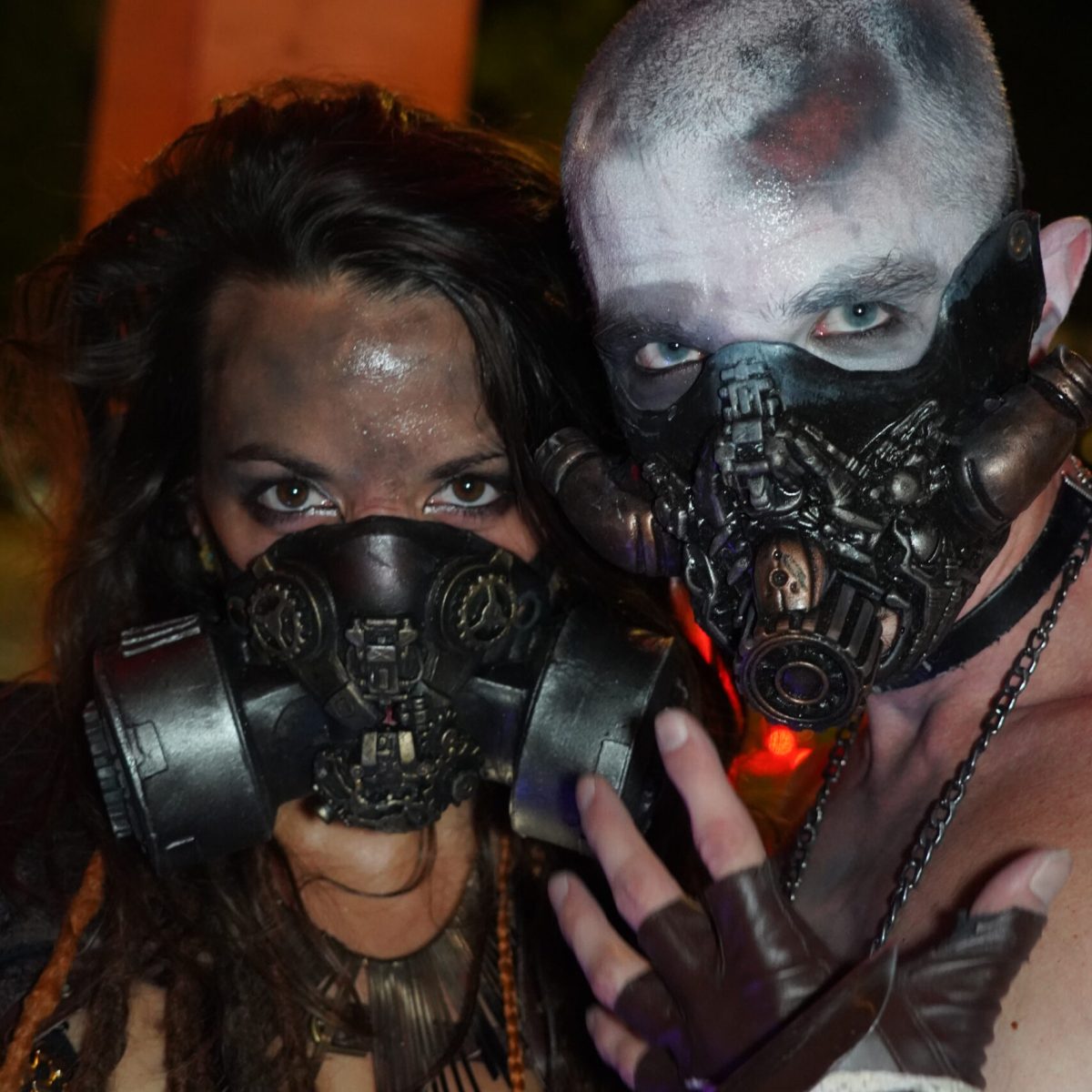 Un homme et une femme en costume de Mad-Max (post-apocalyptique) avec un lance-flamme