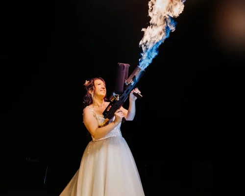 Couple de mariés posant devant des effets de feu et des étincelles pyrotechniques.