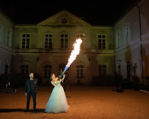 Show de feu nocturne devant la façade d'un domaine de mariage en Rhône-Alpes.