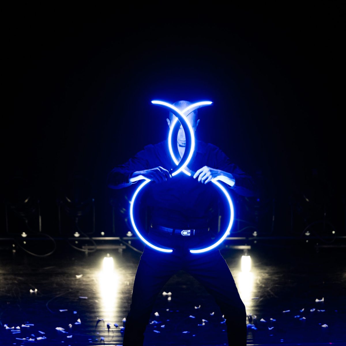 Un artiste sur scène qui manipule des buugeng LED (lumineux) de couleur bleue