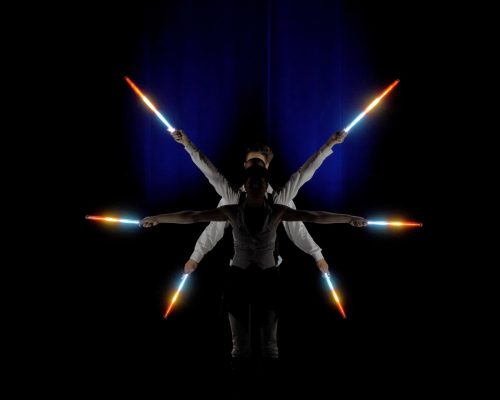 Trois artistes l'un derrière l'autre avec des pixel poi allumées de couleurs rouge et bleu pour former une étoile