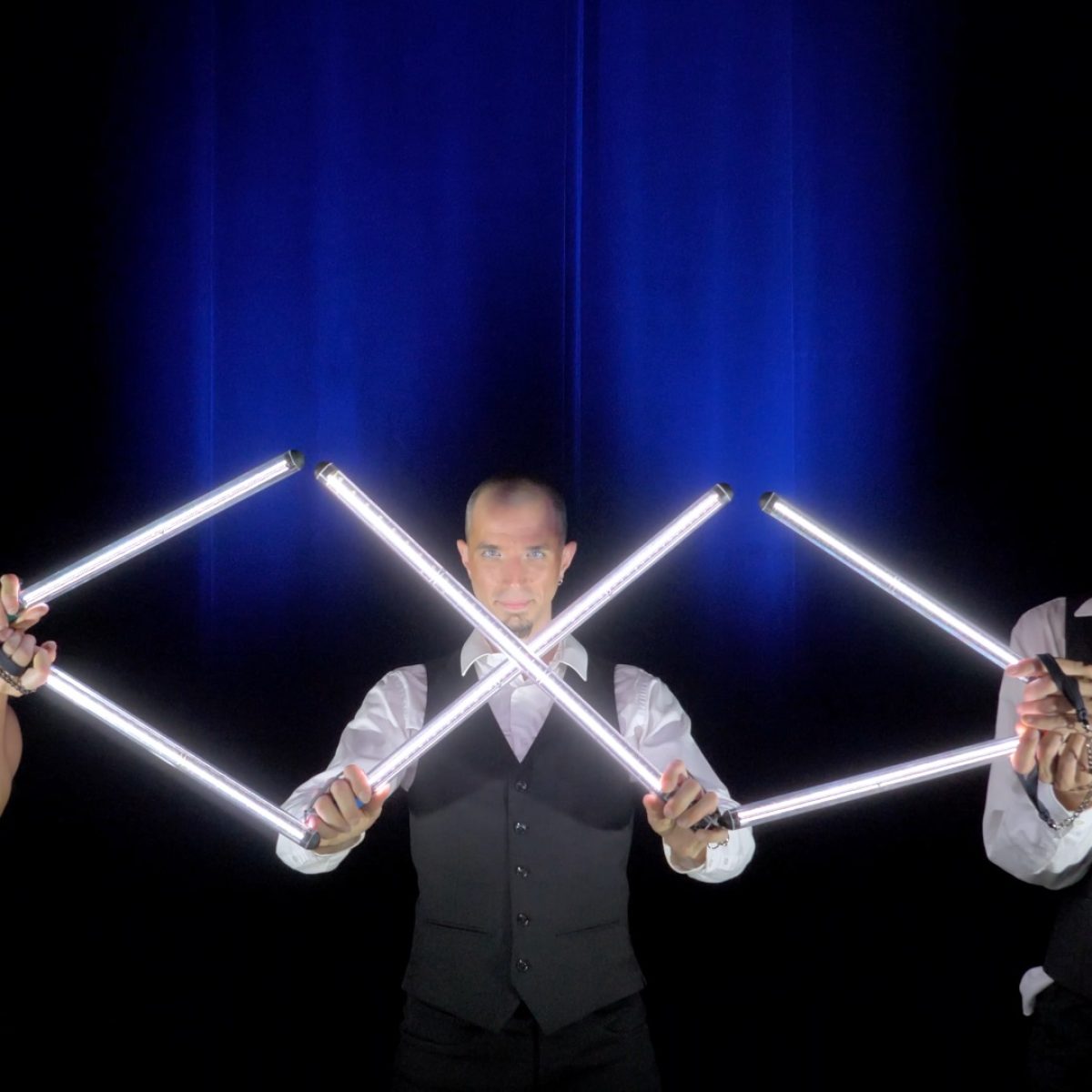 Trois artistes côte-à-côte sur scène avec des pixels poi lumineuses positionnées de manière à représenter le signe de l'infini